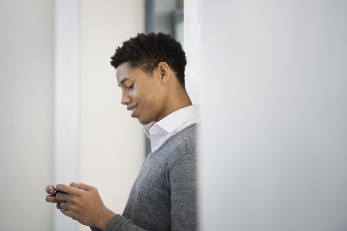 Urban Lifestyle,USA,A young man in a grey sweater using his mobile phone.